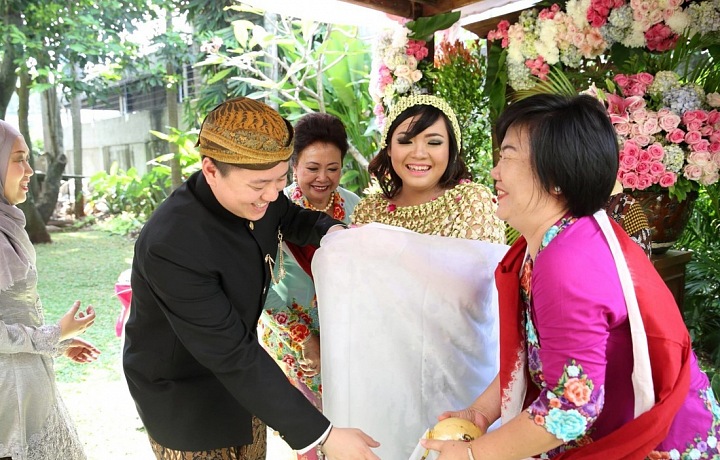 Naloni Mitoni - budoucí matka je zahalena sedmi vrstvami batiky, což symbolizuje naději, že dítě bude zdravé a porod bezproblémový.