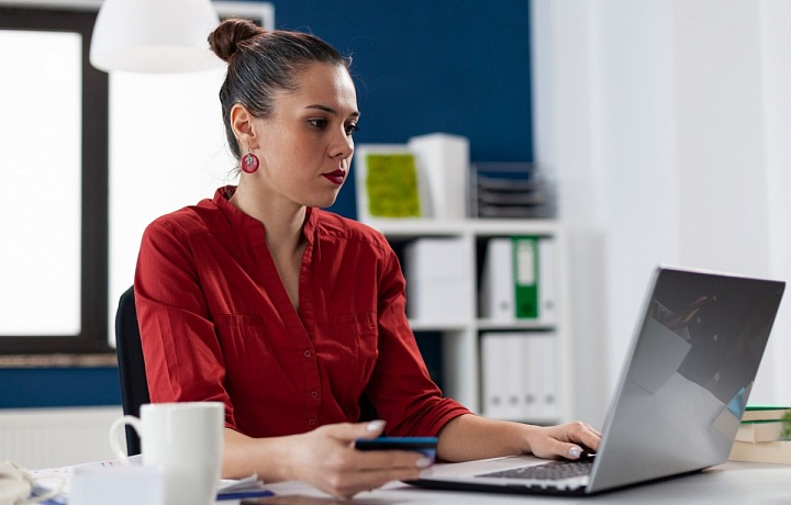 Žena v kanceláři pracující na laptopu.