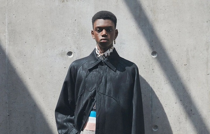 Muž v šortkách a černém kabátu Dior