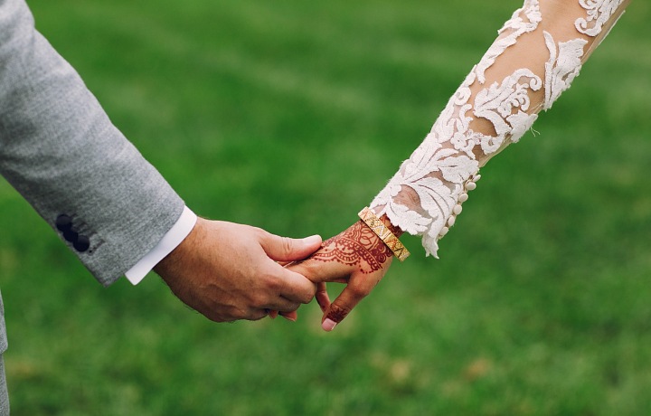 Novomanželka si zlatý náramek přendává z ruky na ruku