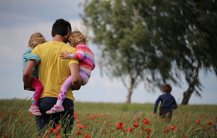 Táta nesoucí své děti na rukou.