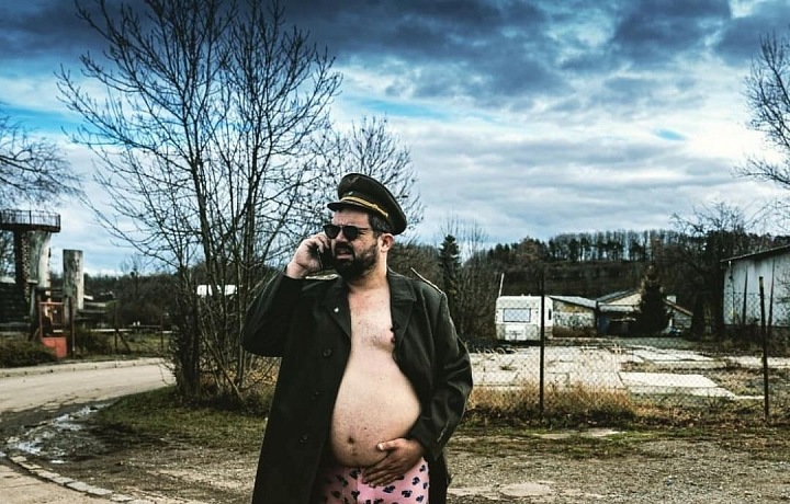 Novotný v trenýrkách a kabátě telefonuje. 