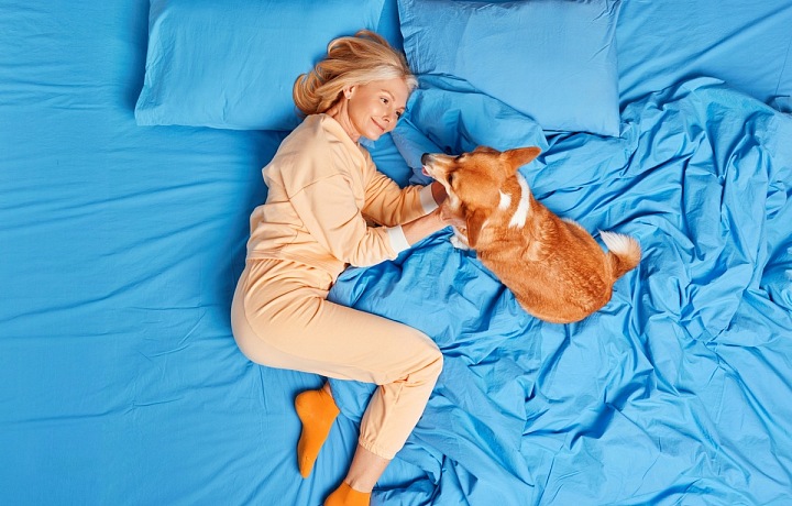 Žena se mazlí se psem v posteli