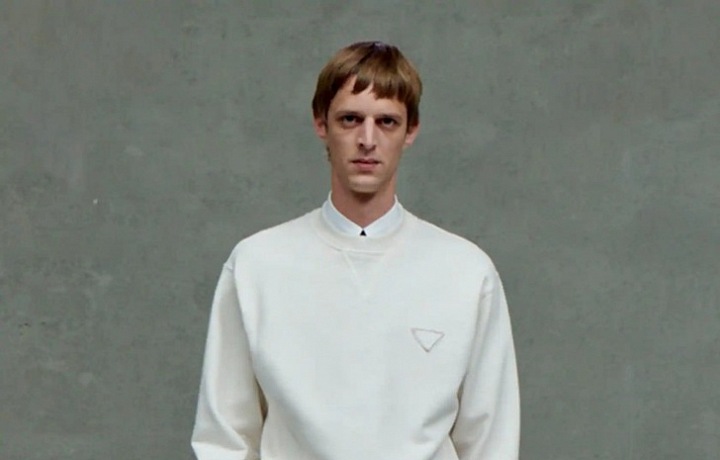 Muž v bílých kalhotách a mikině Prada