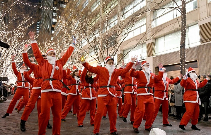 Prodavači v obchodě Marunouchi a pracovníci v kostýmech Santa Clause tančí během vánočního doprovodu v nákupní čtvrti Marunouchi v Tokiu