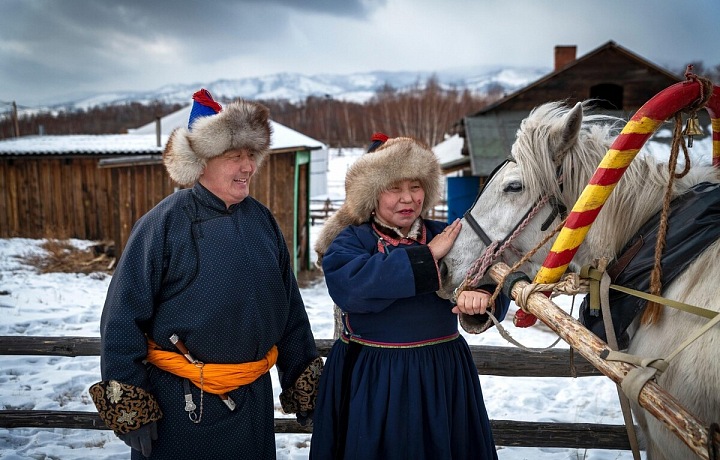 Pár Burjatů v tradičních kostýmech s koněm