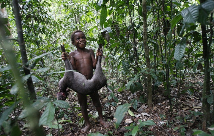 Dívka z kmene Mbuti v Tunduoloki drží právě ulovenou zvěř.