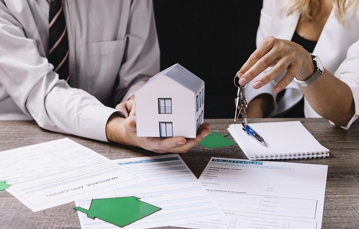 Muž s modelem domu v ruce.