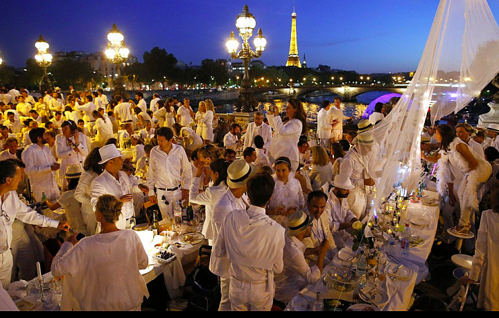 Lidé oblečeni v bílé, oslavují bílou noc v Paříži.