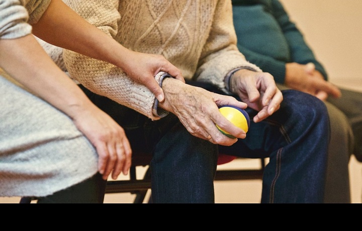 Ruce sedících seniorů, jeden drží míček