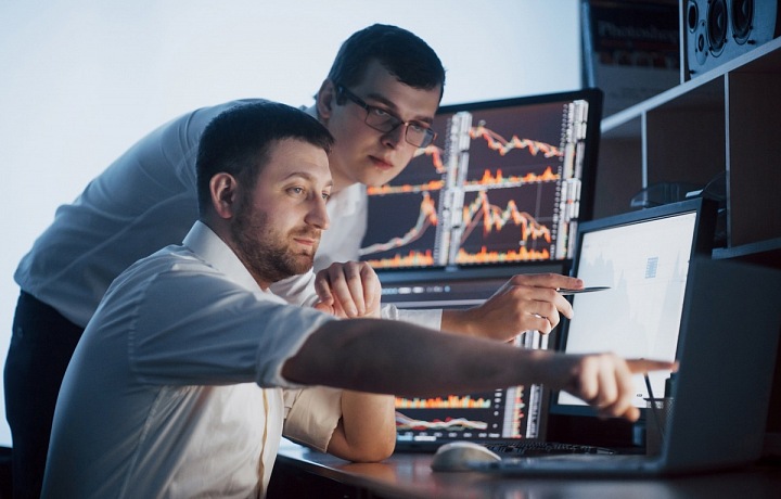 Dva muži u počítačů diskutující ekonomický vývoj.