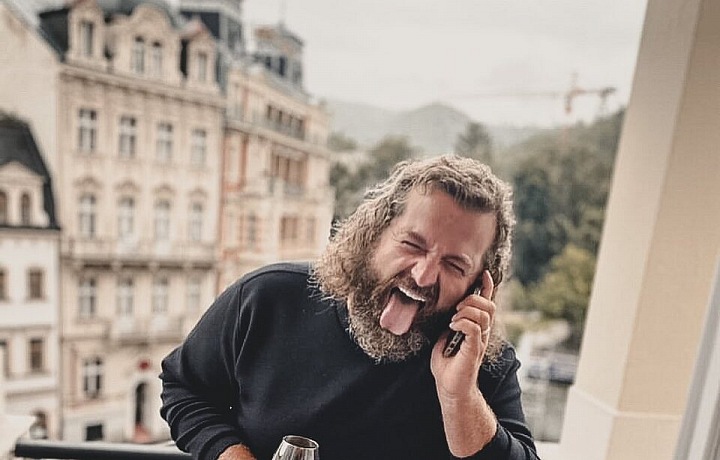 Josef  Maršálek se sklenicí vína a vypláznutým jazykem. 