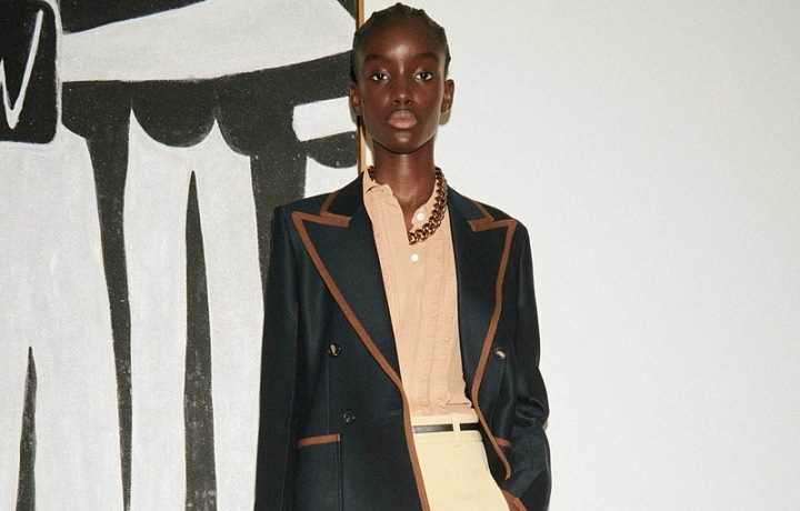 Žena v krémových kalhotých a saku Victoria Beckham