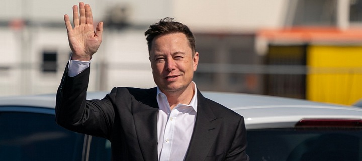 Elon Musk stojí ve tmavém obleku