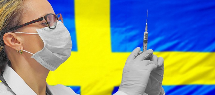 Lékařka s injekční stříkačkou v pozadí se švédskou vlajkou