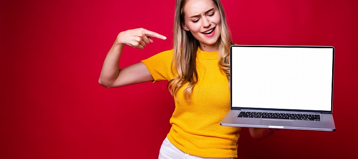 Smějící se mladá dívka ukazuje na laptop v ruce