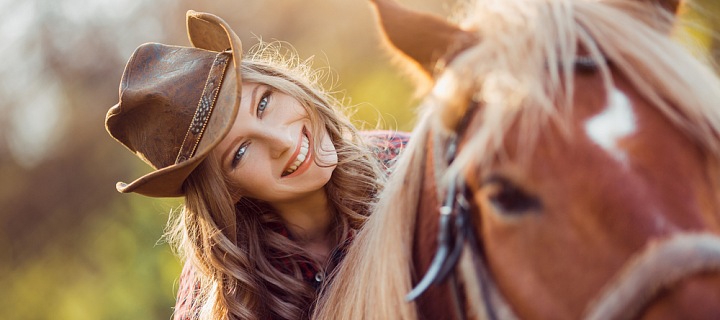 Žena v klobouku sedí na koni