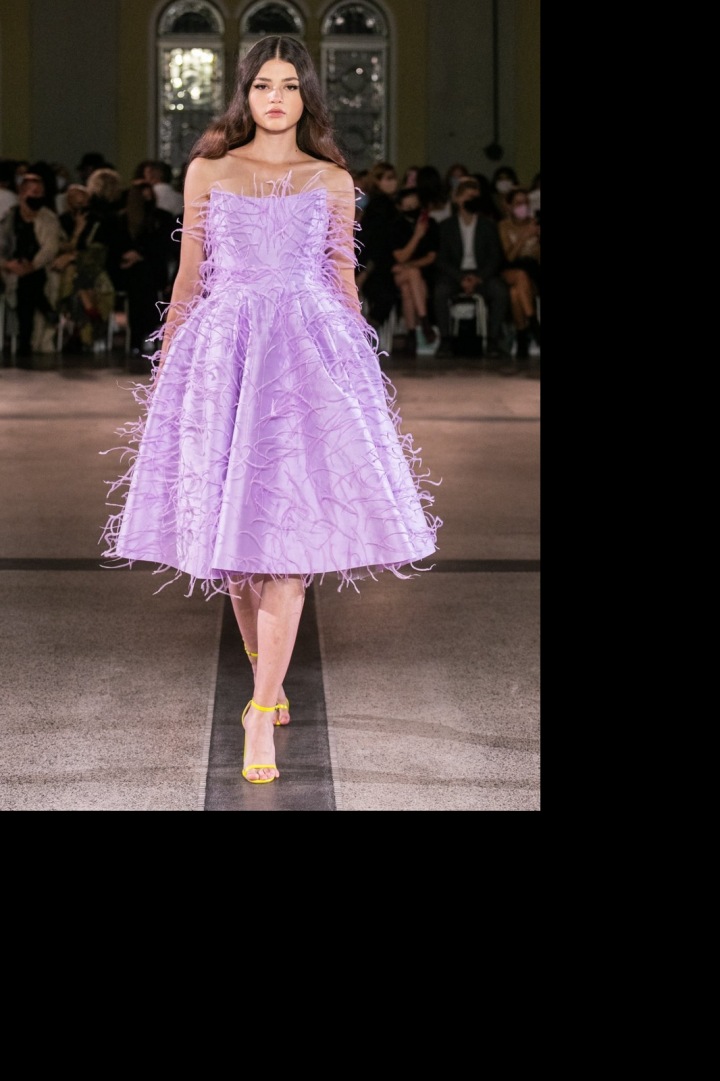 Modelka má na sobě kratší šaty pošité pírky od Vandy Jandy