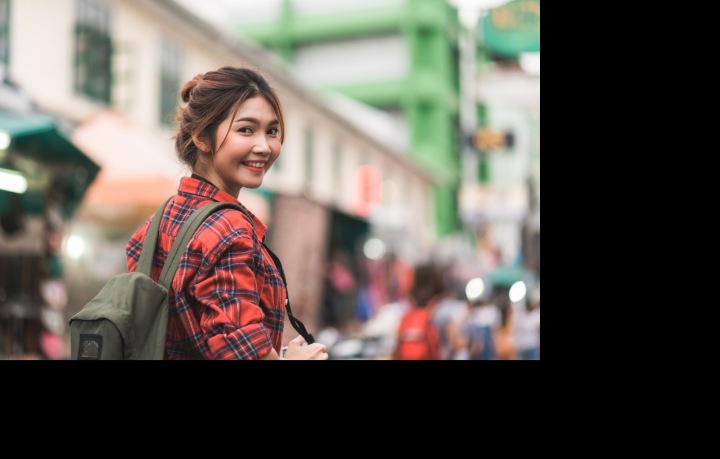 Asiatka v kostkované košili stojí na ulici a usmívá se Asiatka v kostkované košili stojí na ulici a usmívá se