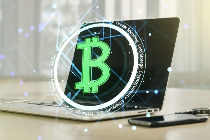 Symbol bitcoinu s laptopem v pozadí Symbol bitcoinu s laptopem v pozadí