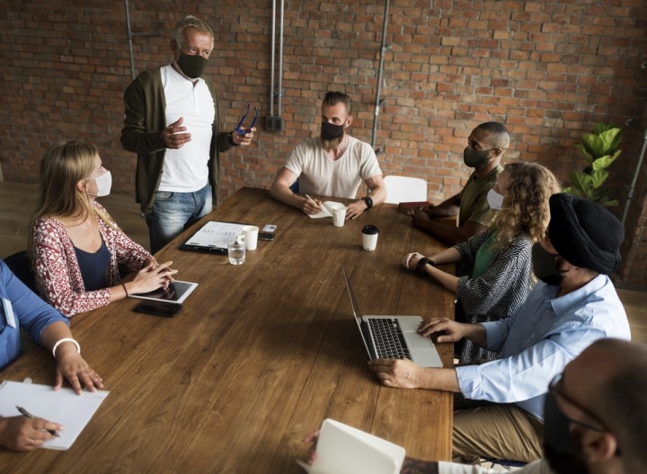 Zaměstnanci na pracovním mítinku, všichni v maskách 