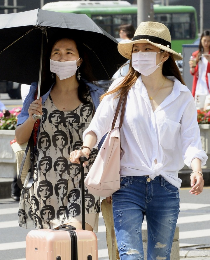 Číňanky mají na tvářích ochranné masky ve smogem zamořeném Pekingu.