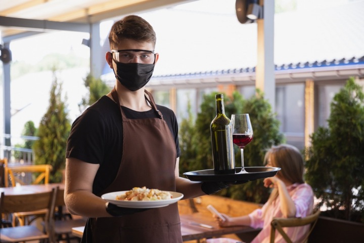 Číšník nese jídlo s rouškou Číšník nese jídlo s rouškou
