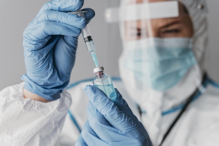 Doktorka v ochranném obleku nabírá vakcínu Doktorka v ochranném obleku nabírá vakcínu