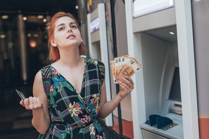 Emocionální dívka u bankomatu s kartou a eury v rukou 