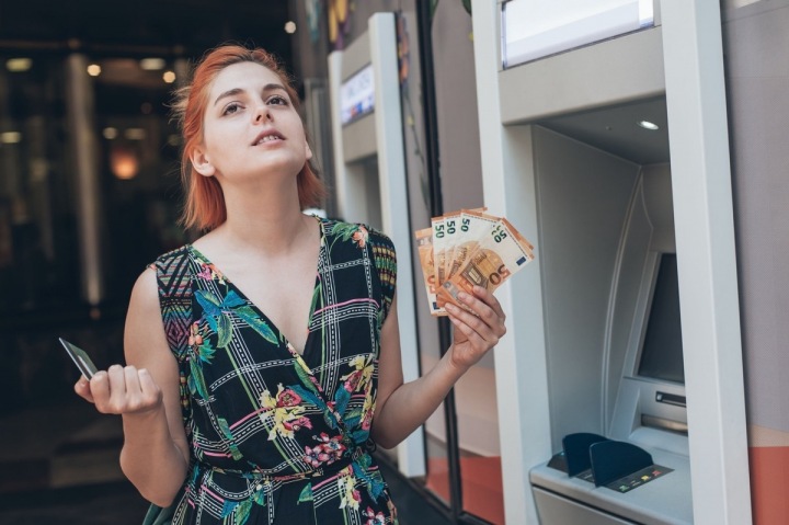 Emocionální dívka u bankomatu s kartou a eury v rukou Emocionální dívka u bankomatu s kartou a eury v rukou