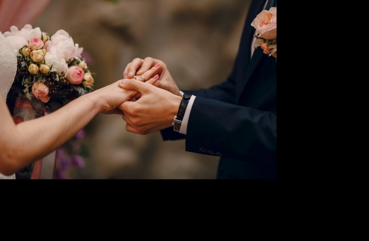 Ruce novomanželů měnících si snubní prsteny