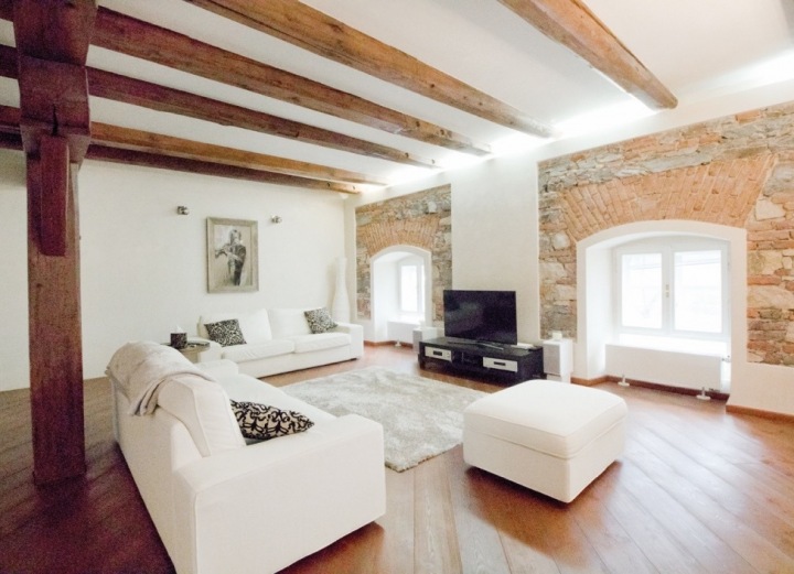 Prostorný obývací pokoj s přiznanými trámy v historické budově v Tróji.