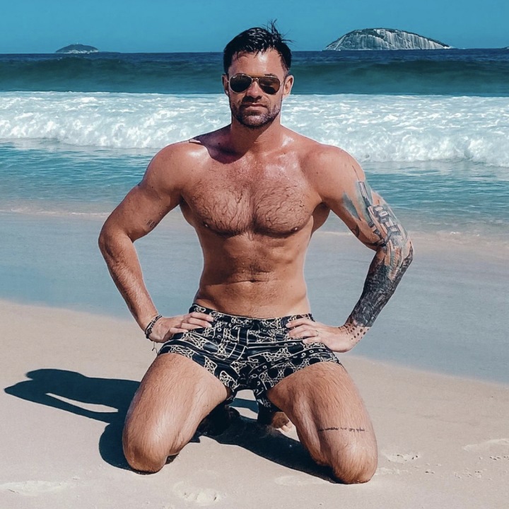 Jan Poborák s vysportovaným tělem klečící na pláži