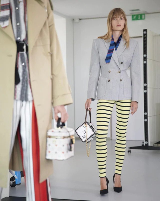 Žena v šedém saku a pruhovaných kalhotách Louis Vuitton Žena v šedém saku a pruhovaných kalhotách Louis Vuitton