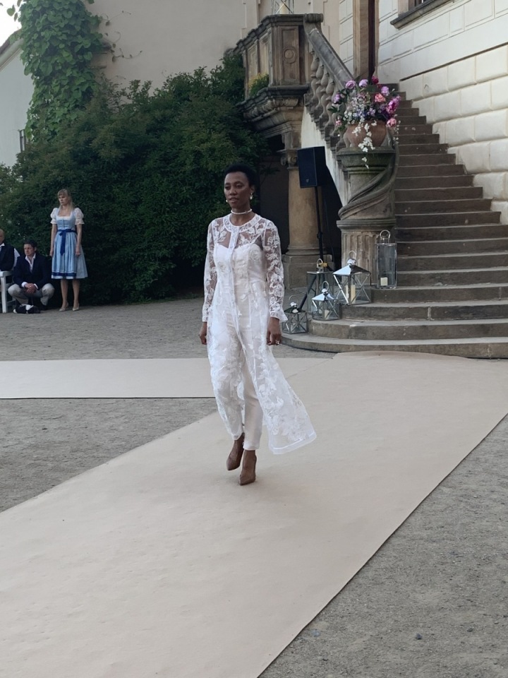 Modelka v bílých kalhotových šatech.