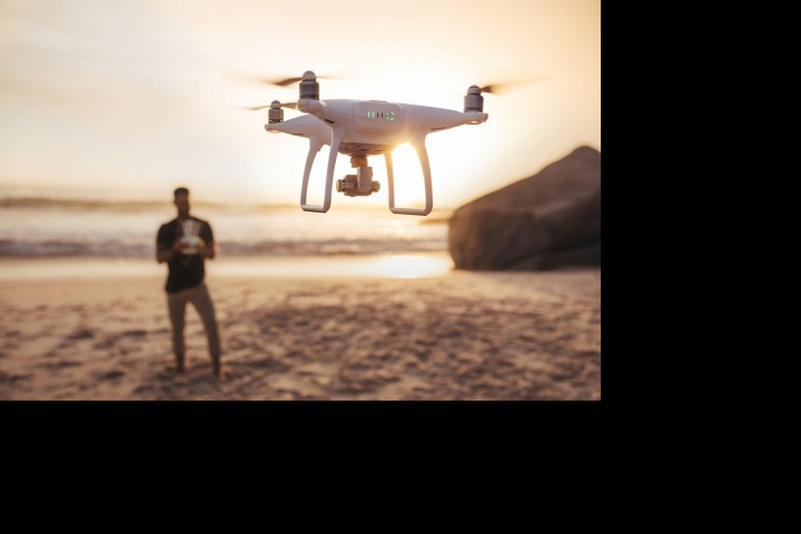 Muž na pláži s dronem Muž na pláži s dronem