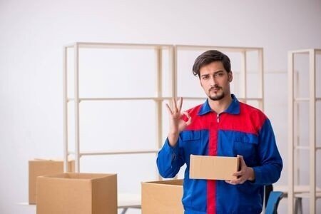 Muž s balky ve skladu ukazuje symbol OK Muž s balky ve skladu ukazuje symbol OK
