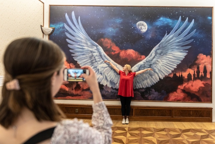 Dívka v muzeu se nechává fotit před obrazem s velkými křídly Dívka v muzeu se nechává fotit před obrazem s velkými křídly