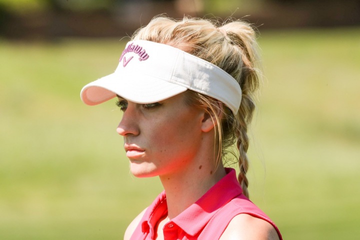 Paige Spiranac na golfovém hřišti z profilu. 