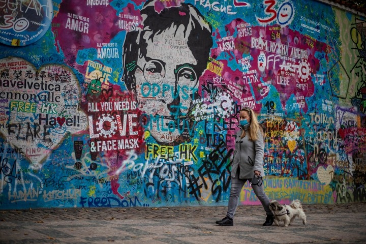 Dívka se psem procházející kolem Lennonovy zdi