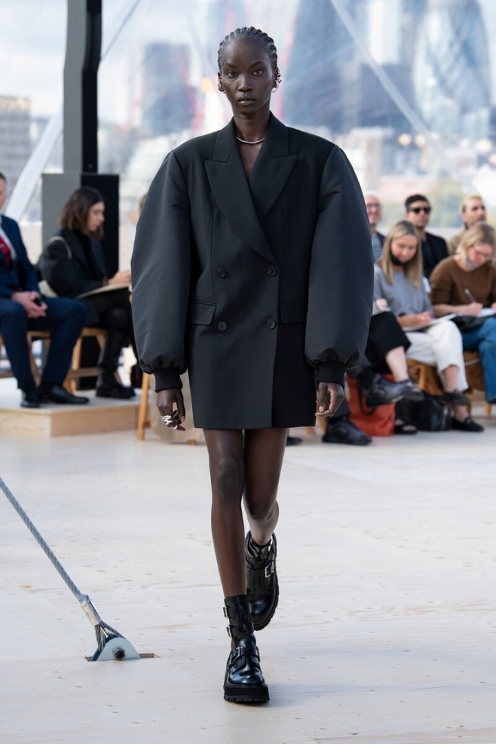 Modelka v černých over size šatech s naducanými balonovými rukávy.