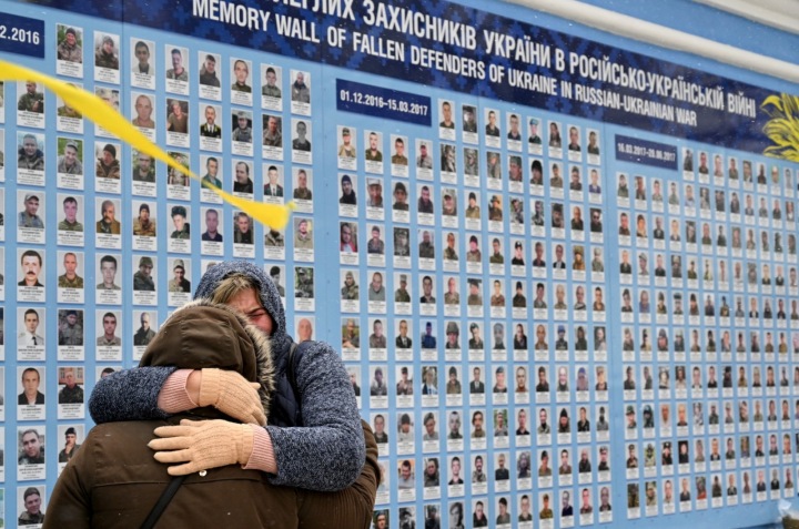 Příbuzní takzvaných Kyborgů, ukrajinských vojáků, kteří padli při obraně doněckého letiště, se objímají u pamětní zdi padlých vojáků v rusko-ukrajinské válce v centru Kyjeva 21. ledna 2022.