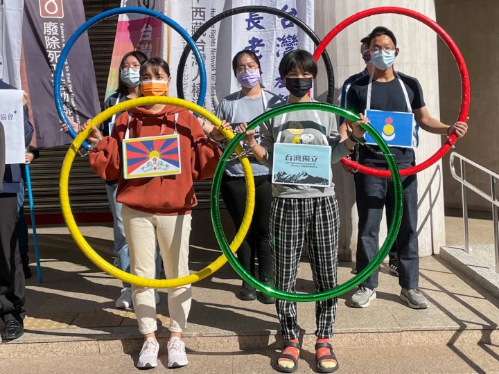 Mladí lidé v maskách držící olympijské kruhy