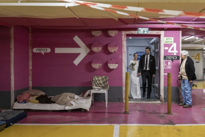 Nevesta a ženích prichádzajú na svadobný obrad do podzemnej garáže slúžiacej ako verejný protiletecký kryt v Tel Avive v Izraeli 