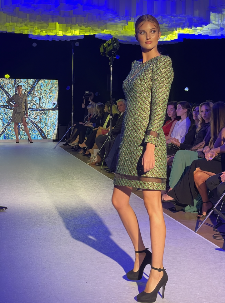 Modelka v zelených šatech s průhlednou aplikací. 