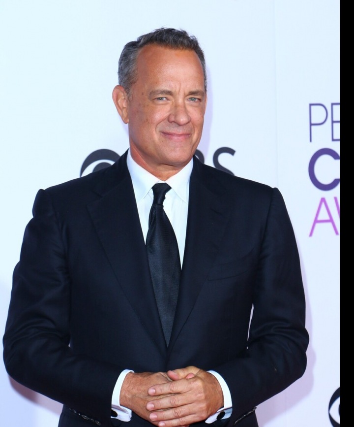 Tom Hanks stojí v tmavém obleku Tom Hanks stojí v tmavém obleku