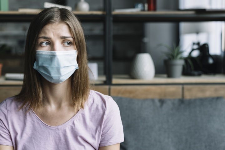 Žena má a tváři roušku a vypadá smutně Žena má a tváři roušku a vypadá smutně