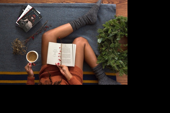 Žena na zemi na dese s kávou a knihami