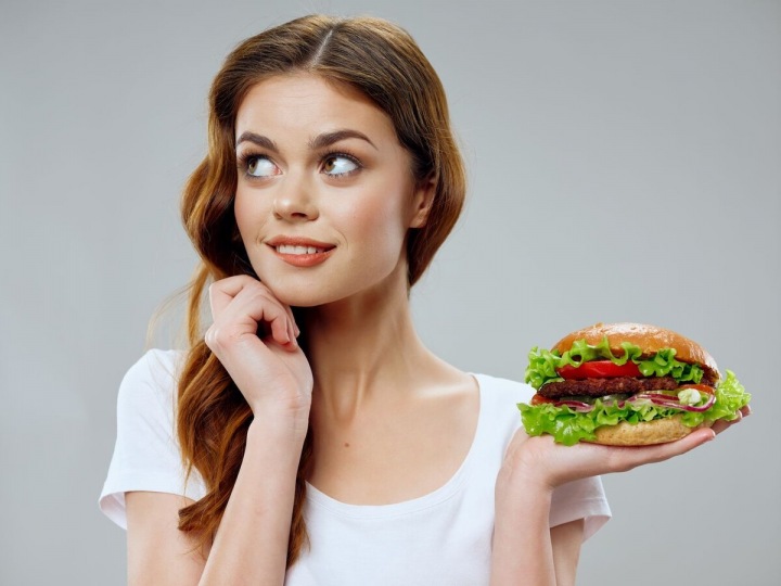 Krásná mladá dívka s hamburgerem v ruce Krásná mladá dívka s hamburgerem v ruce