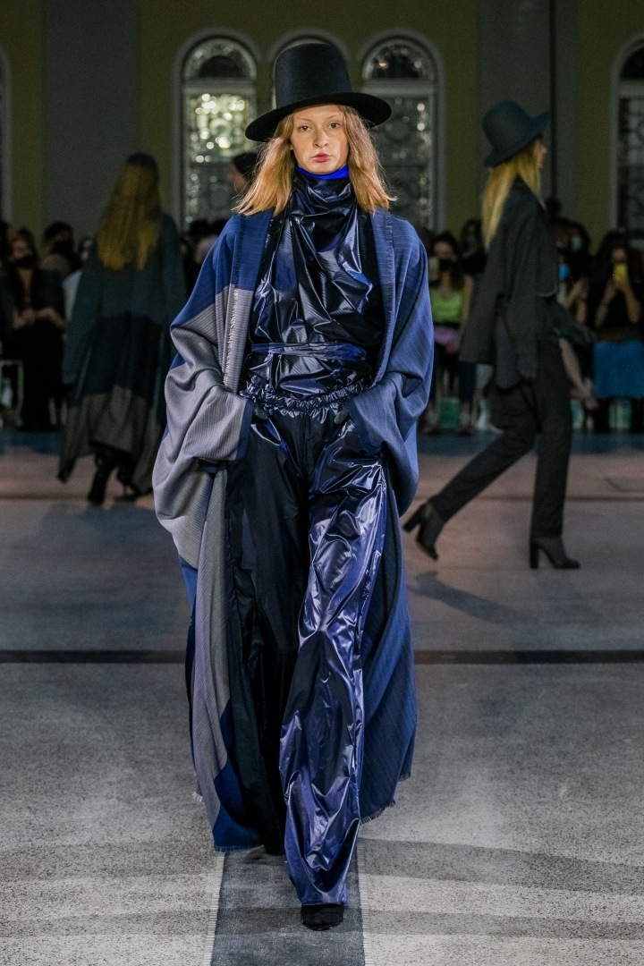 Žena v lesklém moudrém outfitu s černým kloboukem od Jakuba Polanky 